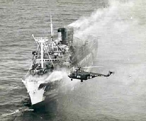 A helicopter from the British aircraft carrier HMS Centaur dropping crewmen to pick up bodies ...jpg